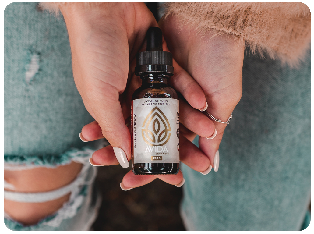 hands_holding_cbd_oilo woman hands holding a bottle of avida CBD oil.