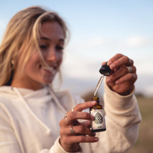 broad spectrum CBD oil being used by a girl. She's taking the dropper out of the bottle filled with broad spectrum CBD oil