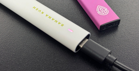 Charging Disposable CBD Vape Pen on table.